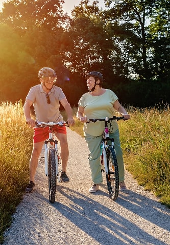 A happy couple riding bicycles through a park