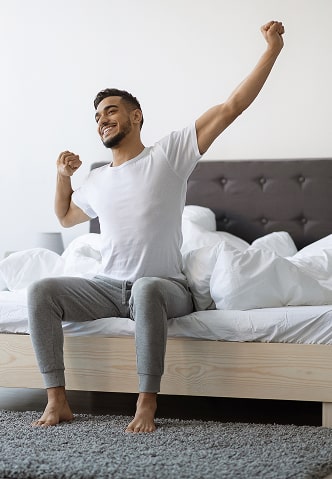 A happy young man stretching after waking up